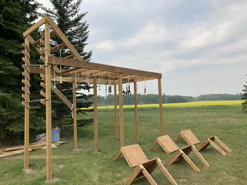 A wooden ninja obstacle course in a green backyard